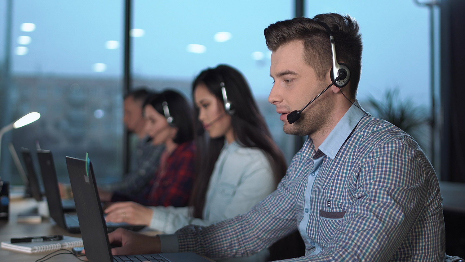 Support desk employees seated at computers with headsets